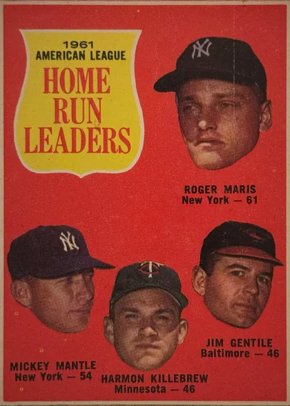 Front of 1962 Topps 1961 AMERICAN LEAGUE HOME RUN LEADERS #53 Base, front of a baseball league leaders card. Red background with a thin off-white border. Upper left has a yellow shield-shaped panel with white outline…