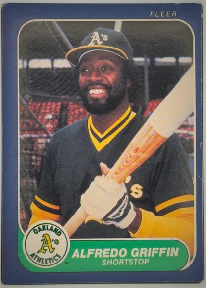 Front of 1986 Fleer Alfredo Griffin #417 Base, front of a Fleer baseball card. A full-color action-style portrait fills most of the card: a smiling Black player with a beard wearing a dark…