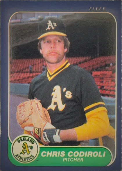 Front of 1986 Fleer Baseball Cards Chris Codiroli #414 Base, portrait-oriented baseball card front. A player in an Oakland Athletics uniform and cap is pictured against a stadium background. The Oakland…