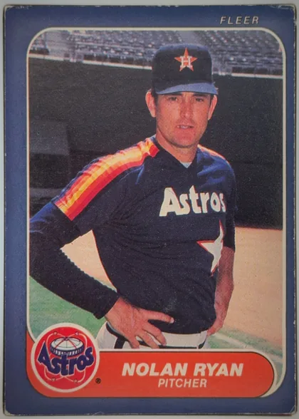 Front of 1986 Fleer Baseball Cards NOLAN RYAN #310 Base, front of a Fleer baseball card. A blue border frames a rounded-corner color photograph of a pitcher standing with hands on hips, wearing a navy…
