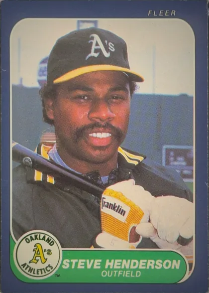 Front of 1986 Fleer Baseball Cards Steve Henderson #419, front of a baseball card. A navy-blue border surrounds a rounded-corner color photograph of a smiling Black outfielder wearing a dark Oakland…