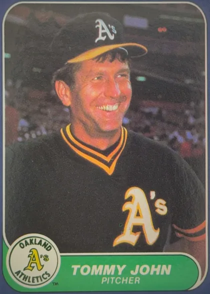 Front of 1986 Fleer Baseball Cards TOMMY JOHN #422 Base, portrait baseball card front featuring Tommy John in an Oakland Athletics uniform and cap. A large player photograph occupies most of the card…