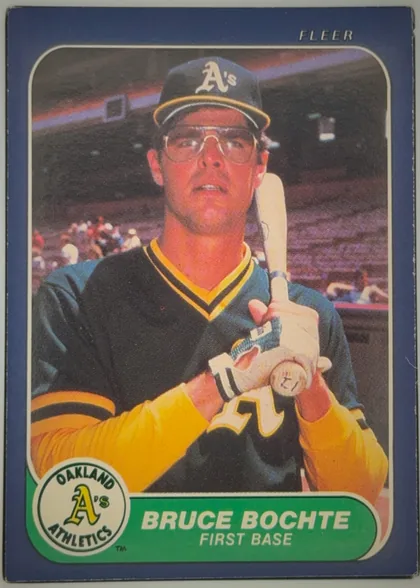 Front of 1986 Fleer Bruce Bochte #413, portrait baseball card front. A player in an Oakland Athletics uniform and batting helmet holds a bat in a stadium setting. FLEER is printed at the…