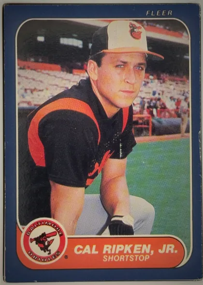 Front of 1986 Fleer CAL RIPKEN, JR. #284 Base, portrait baseball card front. A large color photograph shows a Baltimore Orioles player in uniform seated near the field. The dark blue border…
