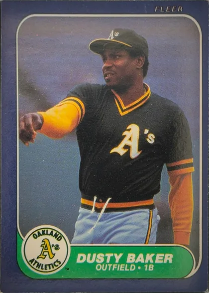 Front of 1986 Fleer Dusty Baker #411 Base, portrait baseball card front. A player in an Oakland Athletics uniform occupies the central photograph. FLEER is printed at the upper right. The…
