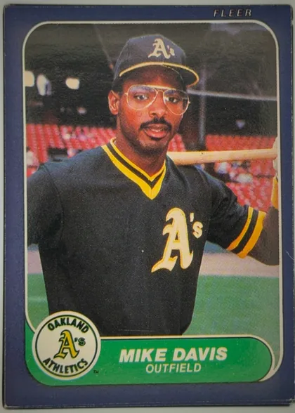 Front of 1986 Fleer Mike Davis #416 Base, upright portrait baseball card. A color photograph of Mike Davis in an Oakland Athletics uniform and cap occupies most of the card. FLEER is printed…