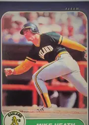 Front of 1986 Fleer Mike Heath #418 Base, front of a baseball card. A navy blue border surrounds a rounded-corner action photograph of a batter in an Oakland A's home uniform (black jersey…