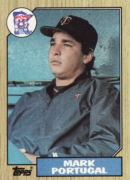Front of 1987 Topps Mark Portugal #419 Base, upright portrait baseball card showing a player in a dark Minnesota Twins cap and jacket against a blue stadium background. A circular Win! Twins!…