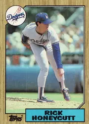 Front of 1987 Topps Rick Honeycutt #753 Base, portrait baseball card front. A Dodgers player in a white uniform is shown pitching in a stadium, with the circular Dodgers logo overlapping the…