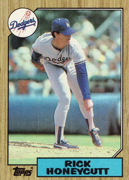Front of 1987 Topps Rick Honeycutt #753 Base, portrait baseball card front. A Dodgers player in a white uniform is shown pitching in a stadium, with the circular Dodgers logo overlapping the…
