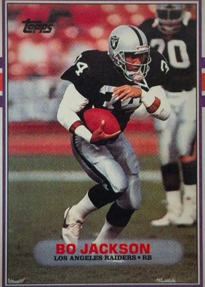 Front of 1989 Topps Football Bo Jackson #269 Base, portrait-format football card front. A large action photograph shows Bo Jackson in a black Los Angeles Raiders uniform carrying a football, with…