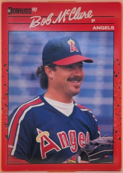 Front of 1990 Donruss Baseball Bob McClure #470, portrait baseball card front. A red speckled border surrounds a large framed color photograph of Bob McClure in an Angels uniform and cap. The…