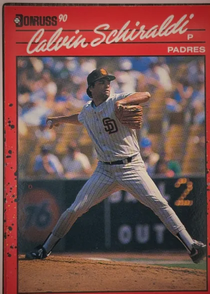Front of 1990 Donruss Baseball Calvin Drew Schiraldi #672, portrait-oriented baseball card front. A red border surrounds a large action photograph of Calvin Schiraldi pitching in a Padres uniform. The…