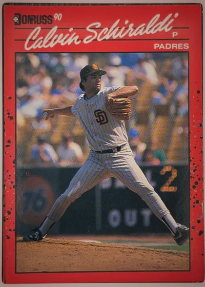 Front of 1990 Donruss Baseball CALVIN DREW SCHIRALDI #672, portrait baseball card front. A large color action photograph shows a San Diego Padres pitcher in a white pinstriped uniform throwing on the field…
