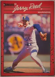 Front of 1990 Donruss Baseball Jerry Reed #614, portrait baseball card front. A red border surrounds a large action photograph of a Mariners pitcher in a blue-and-white uniform delivering a pitch…