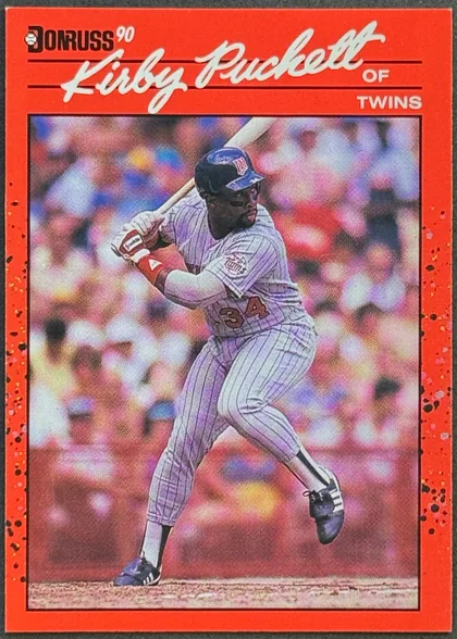 Front of 1990 Donruss Baseball Kirby Puckett #269 Base, portrait baseball card front. A bright red border surrounds a full-color action photograph of Kirby Puckett batting in a Minnesota Twins uniform…