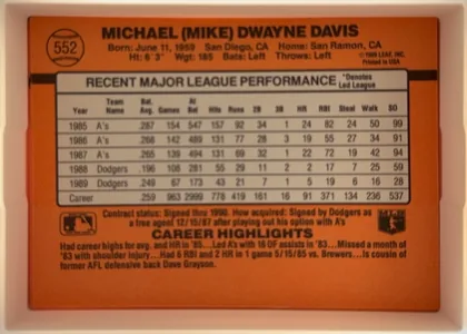 Back of 1990 Donruss Baseball Mike Davis #552, orange baseball-card back with black and gray typography. The player name is centered across the top, with biographical information beneath it. Card…