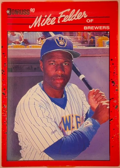 Front of 1990 Donruss Baseball Mike Felder #609, upright portrait baseball card. A bright red border surrounds a large color photograph of Mike Felder in a Milwaukee Brewers uniform holding a bat…