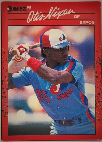 Front of 1990 Donruss Baseball Otis Nixon #456, portrait baseball card front. A red border surrounds a large action photograph of a baseball player in a blue, red, and white Expos uniform swinging…