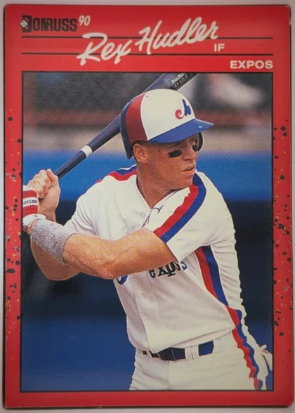 Front of 1990 Donruss Baseball Rex Allen Hudler #366, portrait baseball card front. A red speckled border surrounds a large color action photograph of a batter in a white, red, and blue uniform. The…