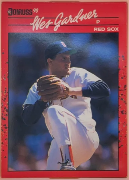 Front of 1990 Donruss Baseball Wes Gardner #541, portrait-oriented baseball card front. A red speckled border surrounds a large photograph of a Boston Red Sox pitcher in a white uniform winding up…