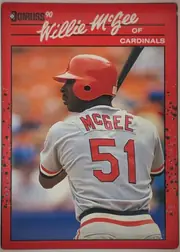 Front of 1990 Donruss Baseball WILLIE DEAN McGEE #632, portrait baseball card front. A red border surrounds a large color action photograph of Willie McGee shown from behind in a Cardinals uniform with…