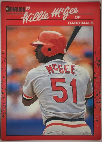 Front of 1990 Donruss Baseball WILLIE DEAN McGEE #632, portrait baseball card front. A red border surrounds a large color action photograph of Willie McGee shown from behind in a Cardinals uniform with…