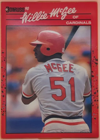 Front of 1990 Donruss Baseball Willie McGee #632, upright portrait baseball card with a predominantly red border. The Donruss 90 logo is at the upper left. Willie McGee appears in profile from…