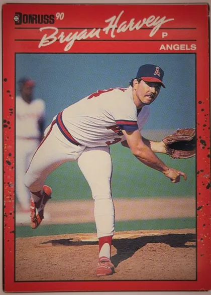 Front of 1990 Donruss Bryan Harvey #372, upright portrait baseball card front. A red border surrounds a large color photograph of a pitcher in an Angels uniform delivering a pitch. The…