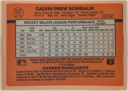 Back of 1990 Donruss Calvin Schiraldi #672, landscape-oriented baseball card back with an orange field and black horizontal stripe. The card number 672 appears inside a baseball graphic at the…