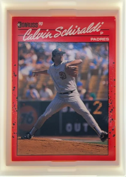 Front of 1990 Donruss Calvin Schiraldi #672, portrait-oriented baseball card front. A red header and border surround a large action photograph of a Padres player pitching. The Donruss logo and…