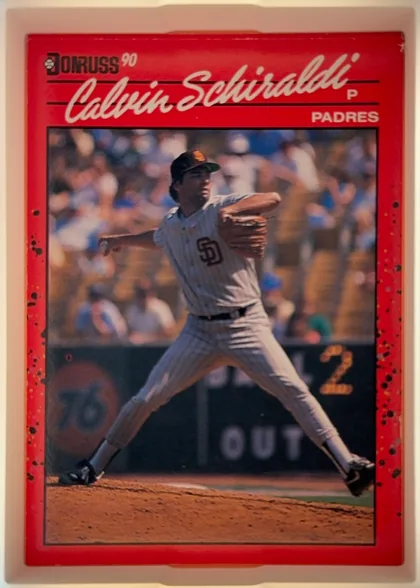 Front of 1990 Donruss Calvin Schiraldi #672, portrait baseball card front. A red border surrounds a large action photograph of Calvin Schiraldi pitching in a San Diego Padres uniform. The upper…
