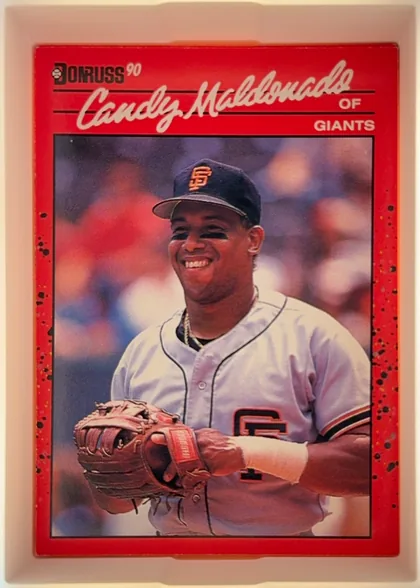 Front of 1990 Donruss Candy Maldonado #611, portrait baseball card front. The Donruss logo and "90" appear at the upper left. A large white script player name, "Candy Maldonado," spans the…