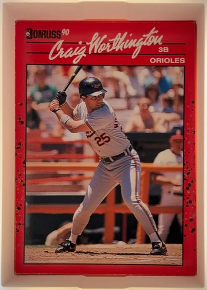 Front of 1990 Donruss Craig Worthington #141, portrait-oriented baseball card front. A Donruss logo and "90" appear at the upper left. The player's large white script name spans the upper…