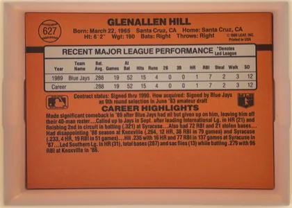 Back of 1990 Donruss Glenallen Hill #627, landscape-oriented baseball card back. The orange design has a black horizontal band behind a centered white statistics panel. GLENALLEN HILL is…