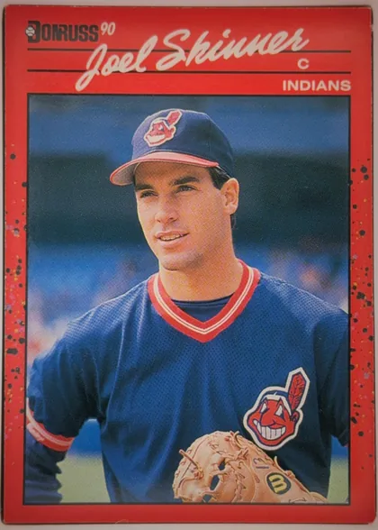 Front of 1990 Donruss Joel Skinner #73, portrait baseball card front. A red border surrounds a large color photograph of a Cleveland Indians player wearing a navy uniform and cap. The…