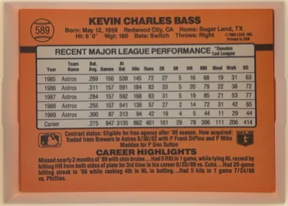 Back of 1990 Donruss Kevin Bass #589, landscape-oriented baseball card back dominated by an orange field. The player name is centered across the top in large dark type. A circular…