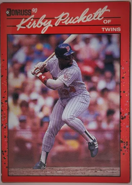 Front of 1990 Donruss Kirby Puckett #269, portrait baseball card front. A large white script player name, "Kirby Puckett," spans the upper section, with "OF" and "TWINS" aligned on the…