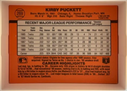 Back of 1990 Donruss Kirby Puckett #269, landscape-oriented baseball card back. An orange-red field surrounds a centered cream statistics table with a black outline. The upper-left contains…