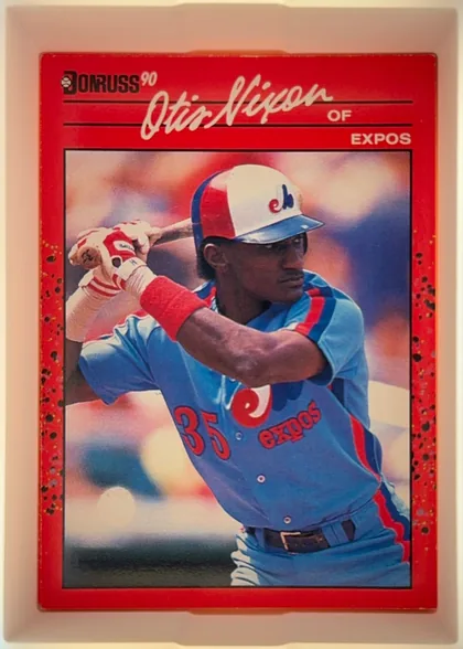 Front of 1990 Donruss Otis Nixon #456, portrait baseball card front. A large color action photograph shows Otis Nixon batting in a Montreal Expos uniform. The top has a red header with…