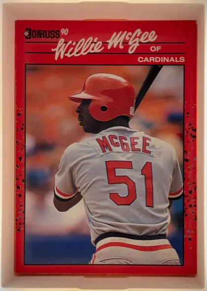 Front of 1990 Donruss Willie McGee #632, upright portrait baseball card. The upper red title area contains the Donruss logo and "90" at left, a large white script "Willie McGee" across the…