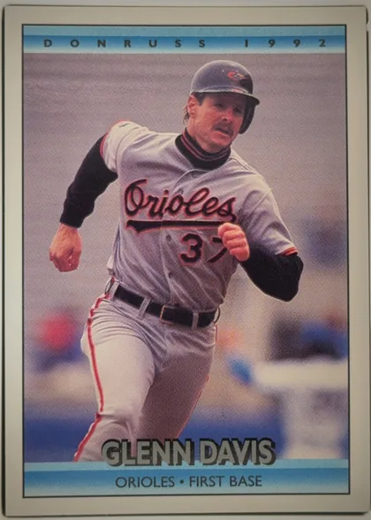 Front of 1991 Donruss Baseball Cards Mickey Tettleton #597, portrait baseball card front. A centered action photograph shows Glenn Davis in a Baltimore Orioles uniform. The top blue gradient band displays…