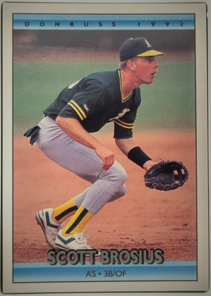 Front of 1991 Donruss Baseball SCOTT DAVID BROSIUS #591, portrait baseball card front. A baseball player in a dark uniform with yellow trim is shown fielding on a dirt-and-grass field. DONRUSS 1992 appears…