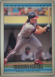Front of 1992 Donruss Baseball Cards Shawn Abner #736, portrait-oriented baseball card front. A color action photograph shows a batter in an Angels uniform swinging at the plate. A blue header band at…