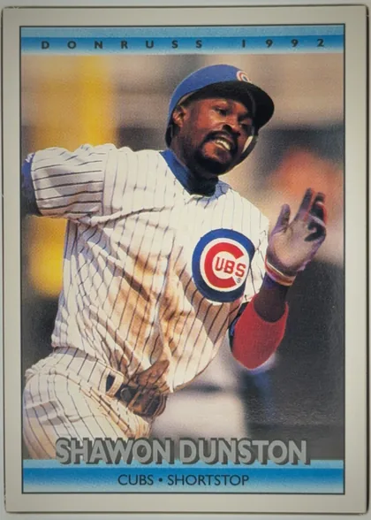 Front of 1992 Donruss Baseball Cards SHAWON DONNELL DUNSTON #613 Base, portrait baseball card front. A color action photograph shows a Chicago Cubs player in a white pinstriped uniform and blue cap, with the Cubs logo…