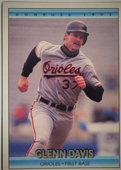 Front of 1992 Donruss Baseball Glenn Davis #597 Base, portrait baseball card front. A color action photograph shows Glenn Davis in an Orioles uniform, running toward the camera. The top blue band reads…