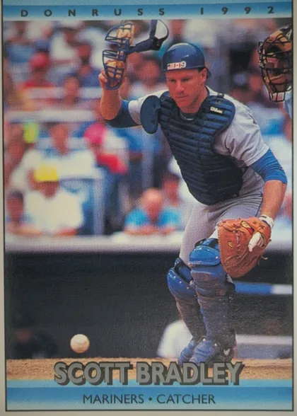 Front of 1992 Donruss Baseball Scott William Bradley #713 Base, upright portrait baseball card. A catcher in full gear is shown in action on the field, with a blurred stadium background. DONRUSS 1992 appears…