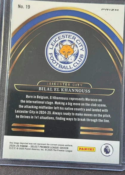 Back of 2024-25 Panini Select Premier League Soccer Bilal El Khannouss #19 Prizm, upright portrait-oriented card back. The upper-left has "No. 19" and the upper-right has "PRIZM." A Leicester City Football Club crest is centered…