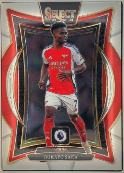 Front of 2024-25 Panini Select Premier League Soccer BUKAYO SAKA #32 Terrace, portrait-oriented soccer card front. A full-body image of Bukayo Saka in an Arsenal red-and-white kit occupies the center. The top has a dark plaque…