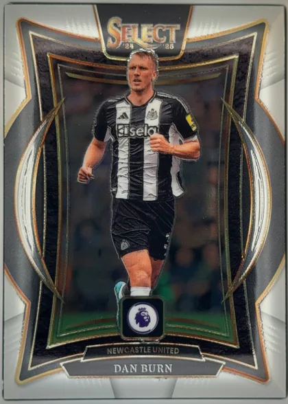 Front of 2024-25 Panini Select Premier League Soccer Dan Burn #87 Terrace, upright portrait soccer card front. A Newcastle United player in a black-and-white kit is shown running centrally within an ornate dark frame. The…